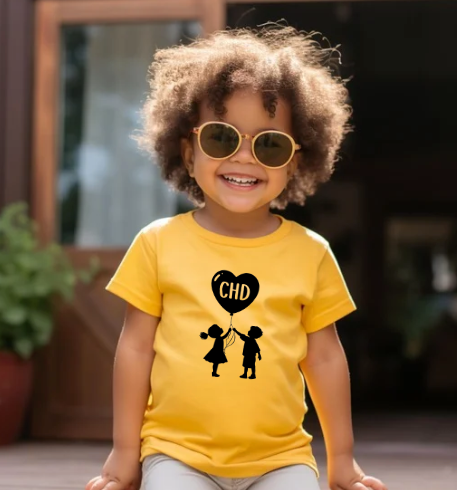 Child wearing a yellow shirt with a black graphic design outdoors